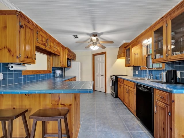 kitchen with dishwasher, tile countertops, freestanding refrigerator, gas stove, and a peninsula