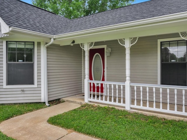 doorway to property with a porch and a shingled roof