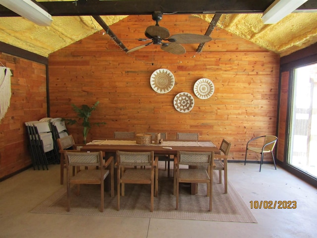 unfurnished dining area with wooden walls, ceiling fan, concrete flooring, and vaulted ceiling