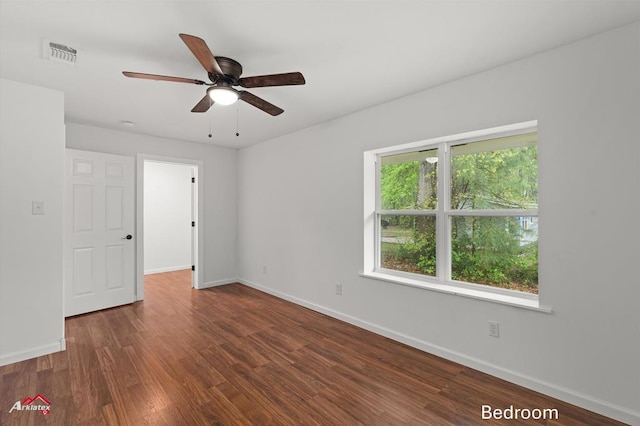 spare room with baseboards, a ceiling fan, wood finished floors, and visible vents