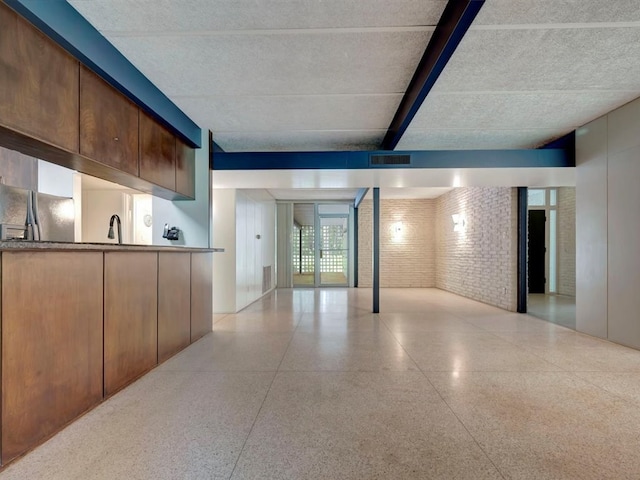 basement with stainless steel refrigerator and brick wall