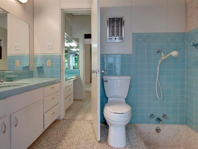 bathroom featuring vanity, toilet, and tile walls