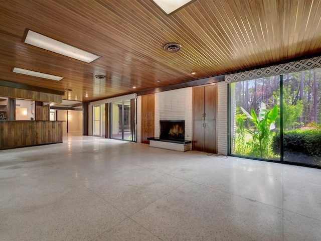 unfurnished living room with wood walls, a large fireplace, and wooden ceiling