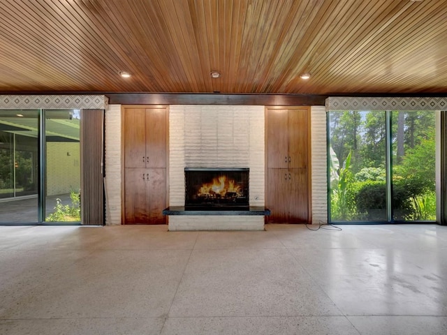 unfurnished living room with wooden ceiling and a brick fireplace