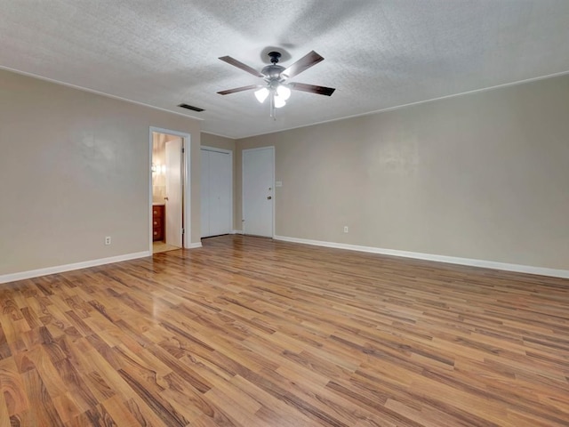 spare room featuring visible vents, baseboards, wood finished floors, a textured ceiling, and a ceiling fan