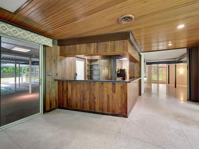 kitchen featuring light speckled floor, wood ceiling, wood walls, and stainless steel refrigerator with ice dispenser