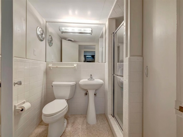 bathroom featuring toilet, tile walls, and a shower with shower door