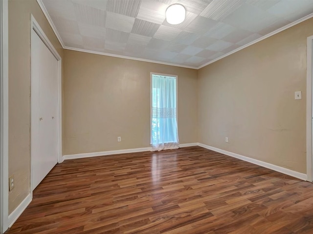 unfurnished bedroom featuring a closet, baseboards, wood finished floors, and crown molding
