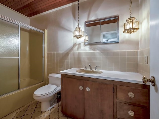 full bathroom featuring combined bath / shower with glass door, vanity, tile walls, tile patterned flooring, and toilet