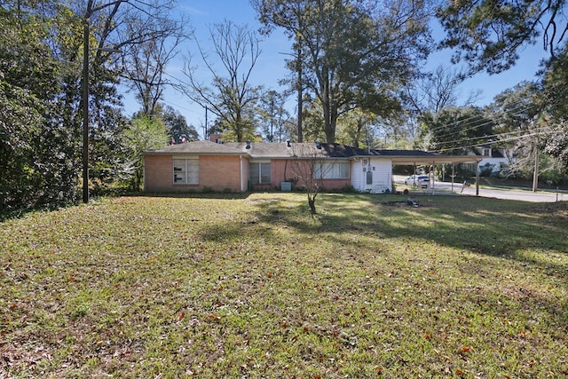 back of house with a carport, brick siding, and a yard