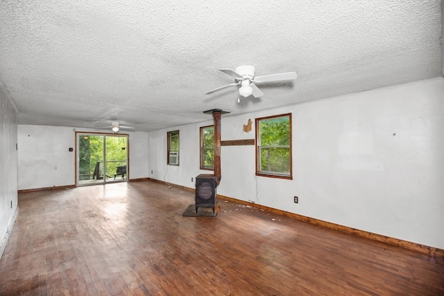 390 County Road 076, Jasper, TX 75951 - empty room with a wood stove, a ceiling fan, wood finished floors, baseboards, and a textured ceiling