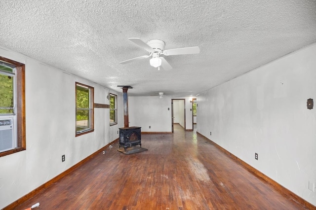 390 County Road 076, Jasper, TX 75951 - unfurnished living room featuring hardwood / wood-style flooring, a wood stove, a ceiling fan, a textured ceiling, and baseboards