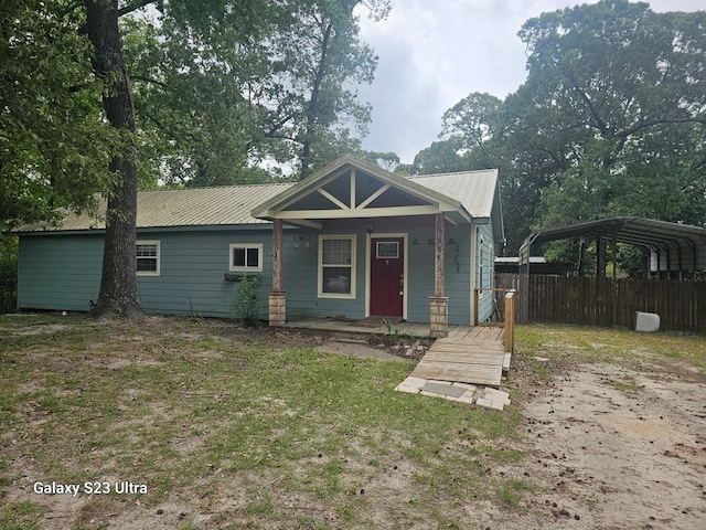 view of front of home featuring fence, a carport, a porch, and metal roof