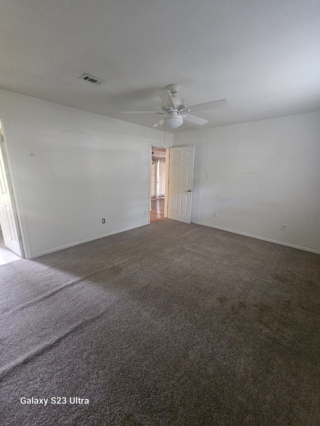 carpeted spare room with baseboards, a ceiling fan, and visible vents