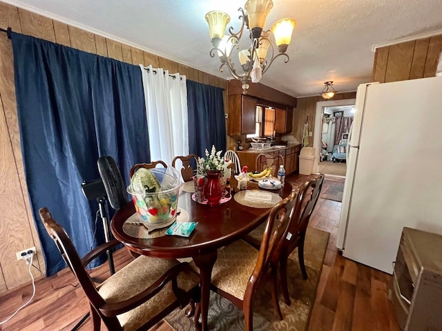 dining room featuring hardwood / wood-style flooring, wood walls, and a chandelier