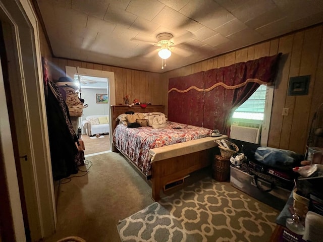 bedroom featuring light carpet, ceiling fan, cooling unit, and wood walls