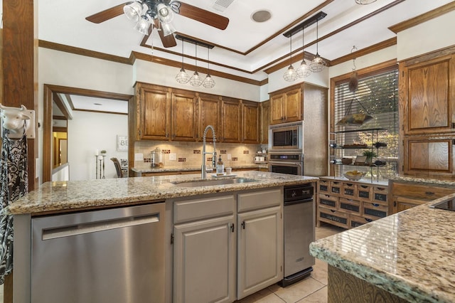 kitchen featuring stainless steel appliances, crown molding, sink, light tile patterned floors, and an island with sink