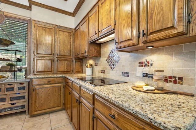 kitchen with tasteful backsplash, light stone countertops, black electric stovetop, and crown molding