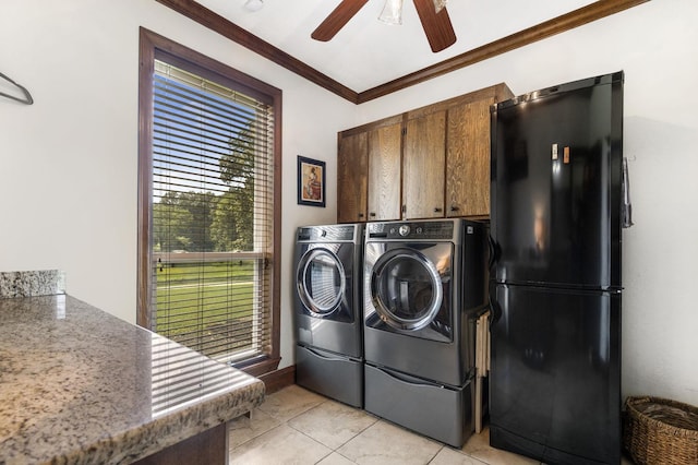 washroom featuring washing machine and clothes dryer, crown molding, light tile patterned flooring, and cabinets