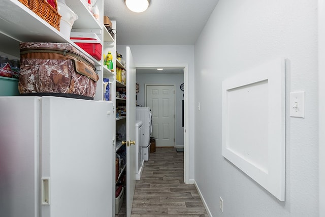 corridor with hardwood / wood-style floors, washing machine and dryer, and a textured ceiling