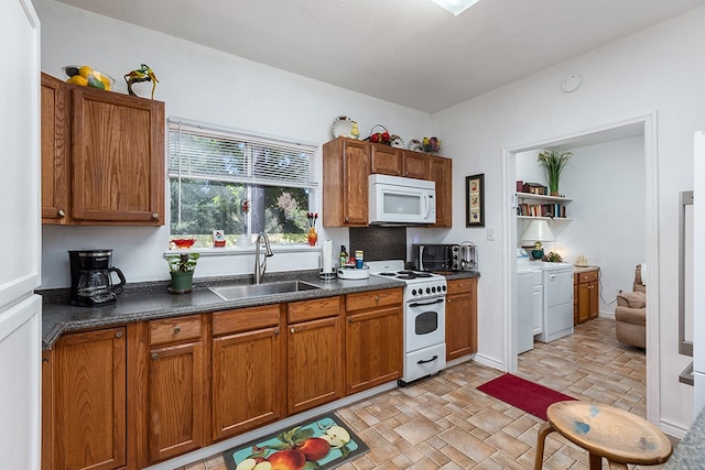 kitchen featuring washer and dryer, white appliances, and sink