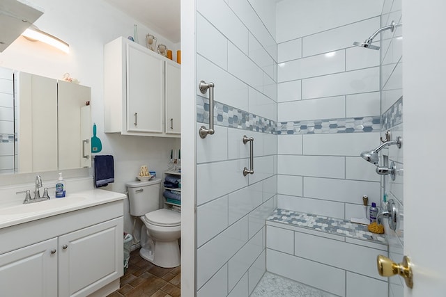 bathroom with a tile shower, vanity, and toilet