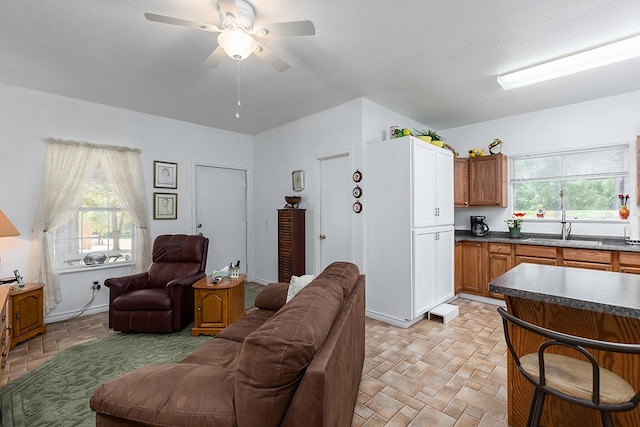 living room with ceiling fan, sink, and a textured ceiling