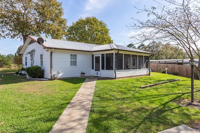 rear view of property featuring a sunroom and a yard