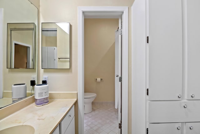 bathroom featuring toilet, tile patterned floors, baseboards, and vanity