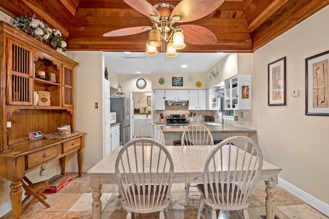 dining area featuring attic access, stone finish floor, ceiling fan, washer / dryer, and baseboards