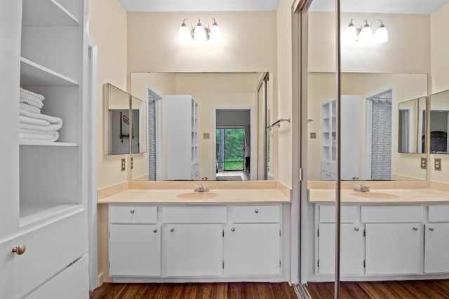 full bath featuring two vanities, a sink, and wood finished floors