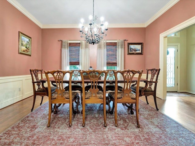 dining room with wood-type flooring, an inviting chandelier, and crown molding