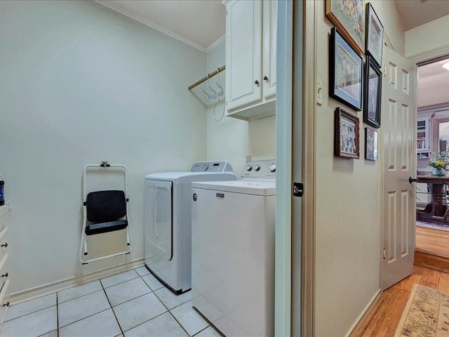 laundry room with washer and dryer, cabinets, crown molding, and light hardwood / wood-style flooring