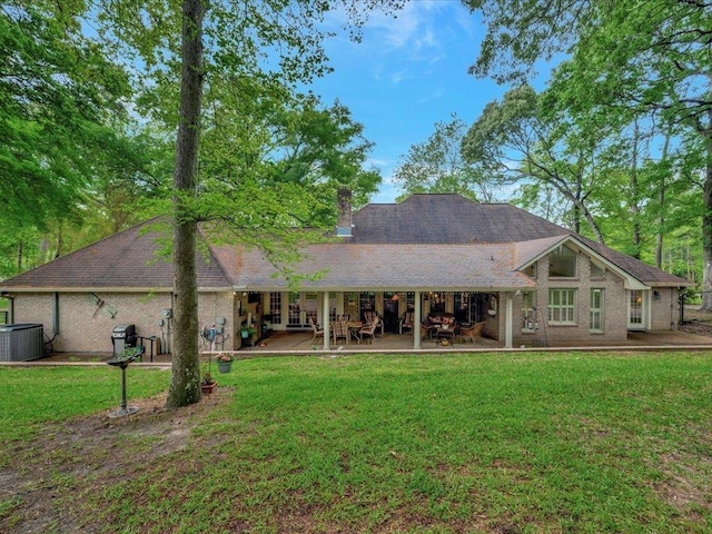 back of house featuring central AC unit, a patio area, and a lawn