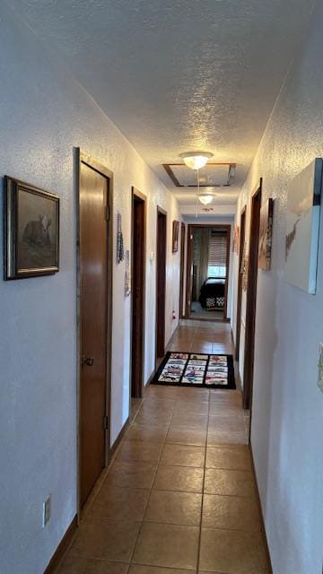 hall featuring tile patterned flooring and a textured ceiling