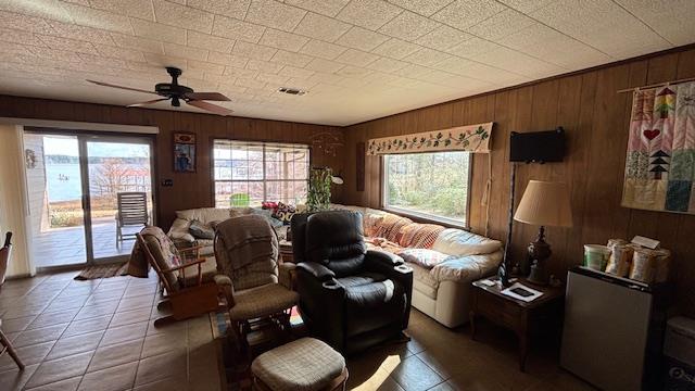 672 Oakhill Rd, Hemphill, TX 75948 - tiled living room with wooden walls and ceiling fan