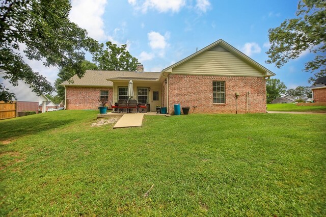 1105 Redbud Ave, Diboll, TX 75941 - back of property featuring brick siding, a patio area, a yard, and a chimney