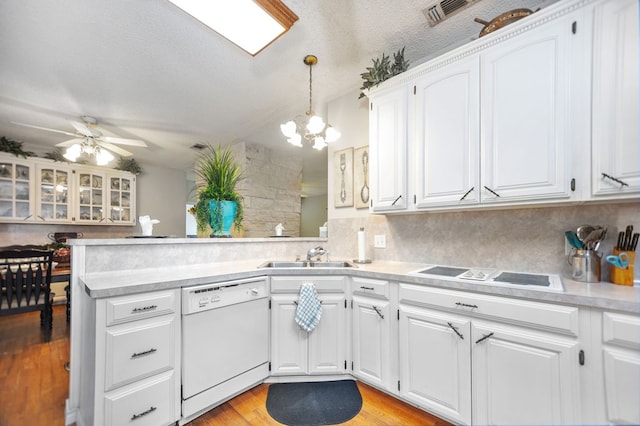 kitchen featuring visible vents, white dishwasher, light countertops, a sink, and a peninsula