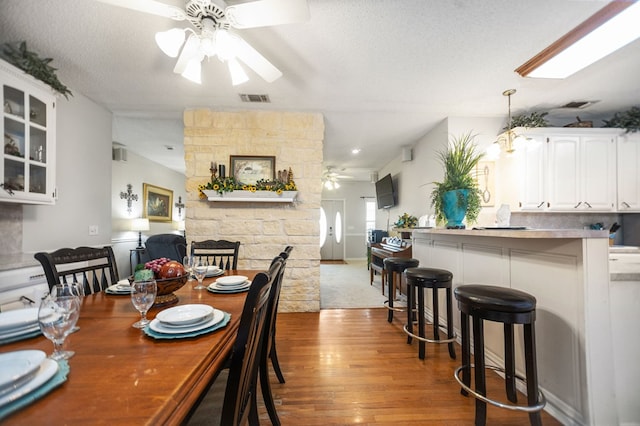 dining space with visible vents, a ceiling fan, a textured ceiling, and wood finished floors