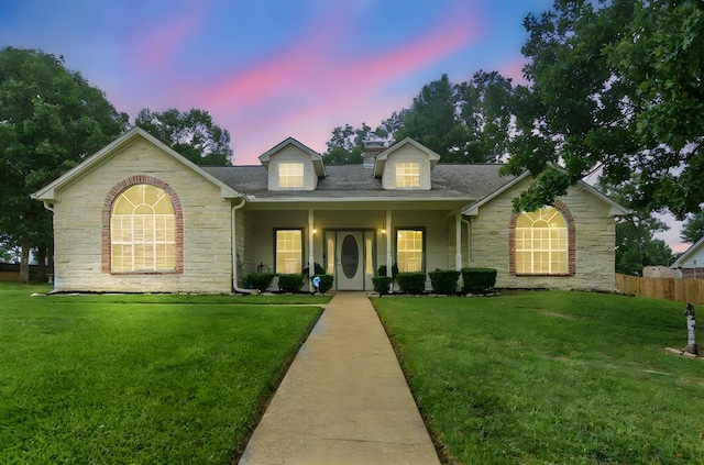 view of front of home with a lawn, fence, and stone siding