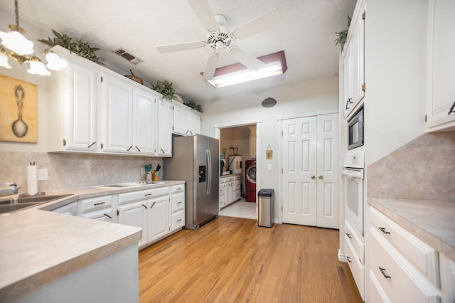 kitchen with white appliances, backsplash, white cabinetry, and light wood finished floors