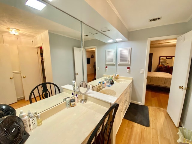 bathroom featuring vanity, ornamental molding, and hardwood / wood-style flooring