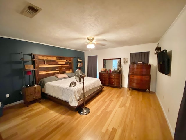 bedroom featuring ceiling fan, light hardwood / wood-style flooring, and ornamental molding