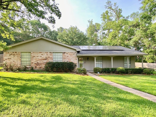 ranch-style house featuring solar panels, a porch, and a front yard