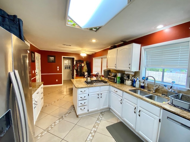 kitchen featuring kitchen peninsula, sink, appliances with stainless steel finishes, light tile patterned flooring, and white cabinetry