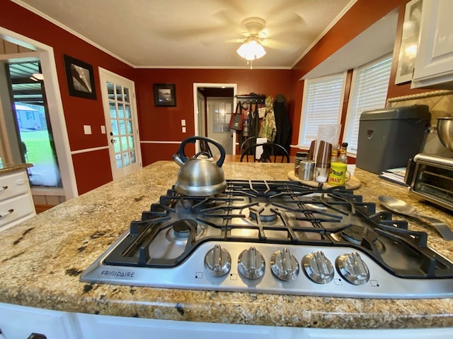 kitchen with white cabinets, ceiling fan, crown molding, and stainless steel gas cooktop