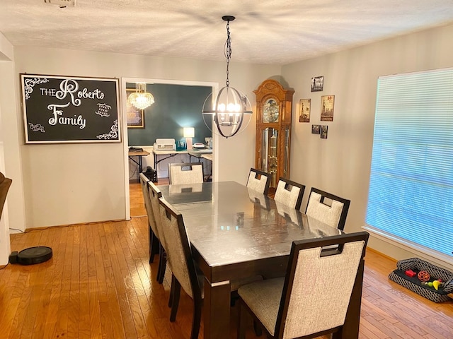 dining area with a chandelier, a textured ceiling, and light hardwood / wood-style flooring