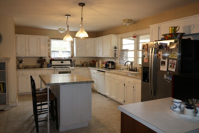 kitchen featuring hanging light fixtures, white appliances, white cabinetry, and a center island