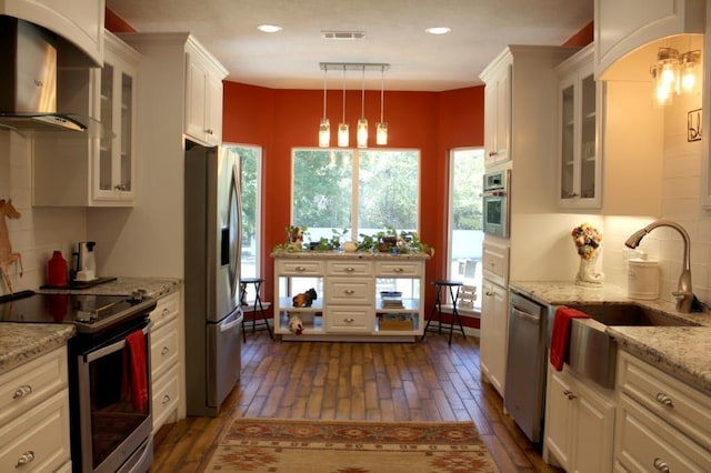 kitchen featuring white cabinets, appliances with stainless steel finishes, hanging light fixtures, and dark wood-type flooring