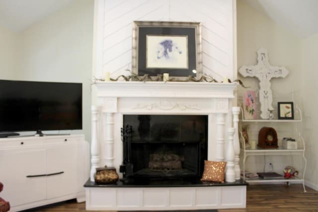 living room with a tiled fireplace, dark wood-type flooring, and lofted ceiling